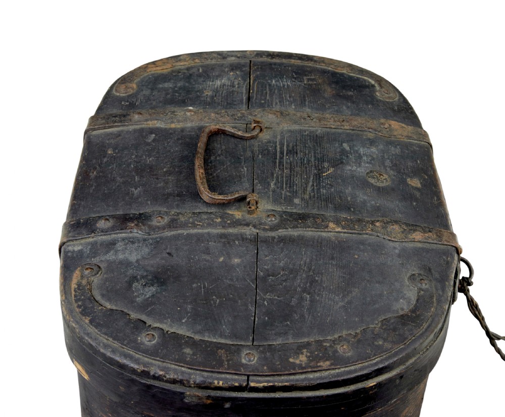 An oval 19th-century Swedish black painted wooden box featuring hand-forged iron straps, side carrying rings, and a key inserted into the central escutcheon. View V