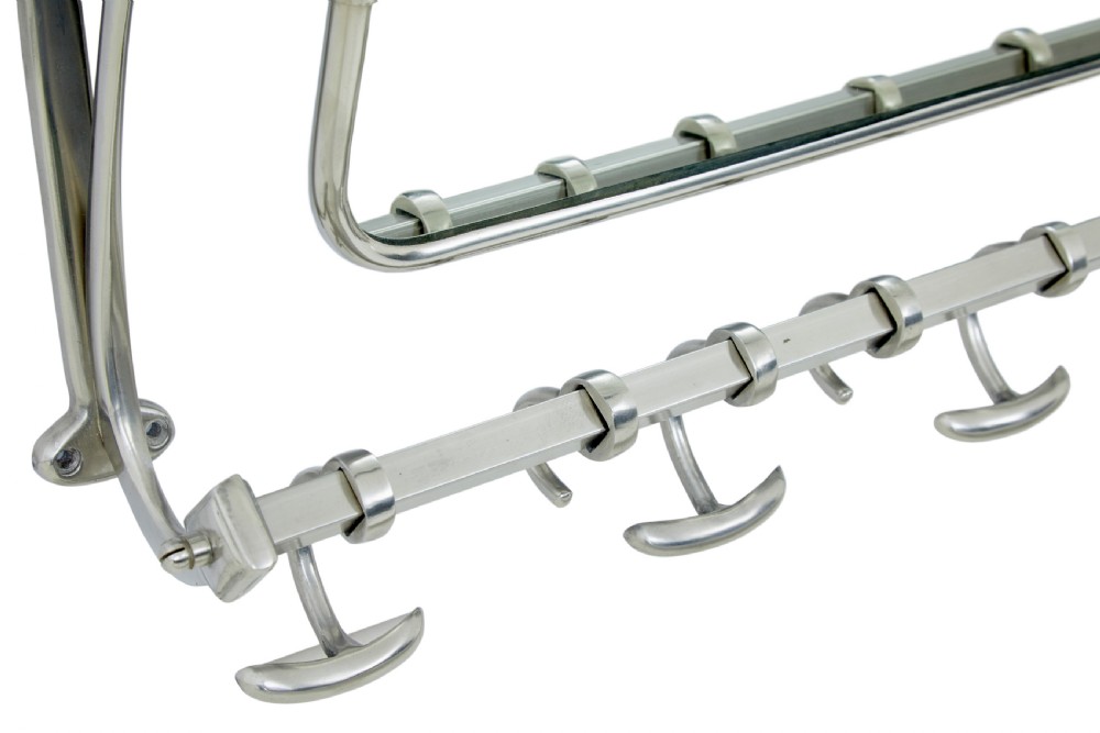 An early 20th-century chromed metal wall rack featuring a central tilting rectangular mirror, a top tubular shelf, and five lower double coat hooks. View IV