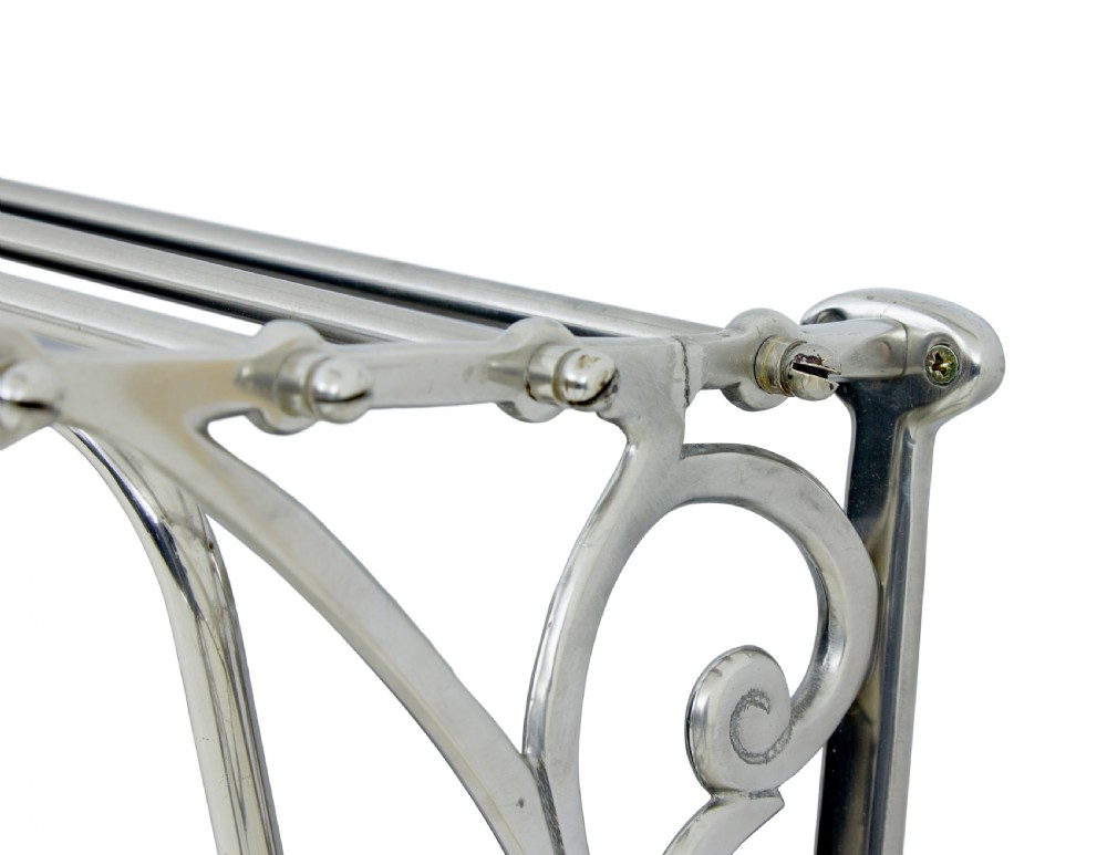 An early 20th-century chromed metal wall rack featuring a central tilting rectangular mirror, a top tubular shelf, and five lower double coat hooks. View VI