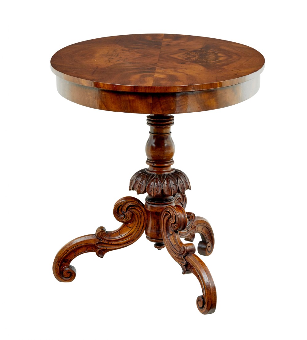 A 19th-century oval wood centre table featuring a figured veneer top, a turned central stem with acanthus leaf carving, and three scroll tripod legs. View II
