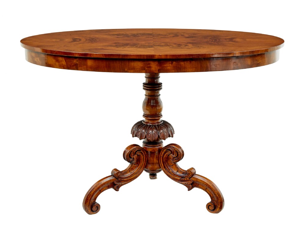 A 19th-century oval wood centre table featuring a figured veneer top, a turned central stem with acanthus leaf carving, and three scroll tripod legs. View III