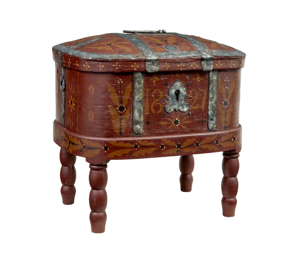 A Swedish folk art painted wooden coffer on turned legs, decorated with red paint, floral motifs, iron straps, and a painted 1827 date.