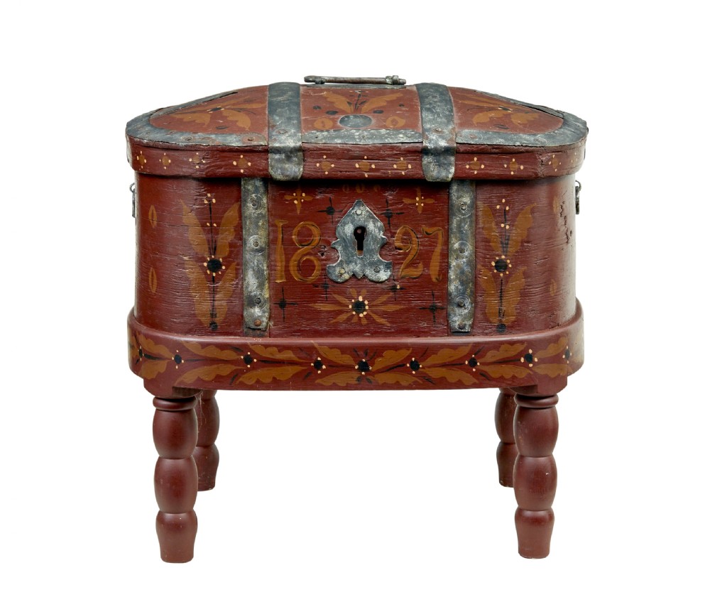 A Swedish folk art painted wooden coffer on turned legs, decorated with red paint, floral motifs, iron straps, and a painted 1827 date. View II