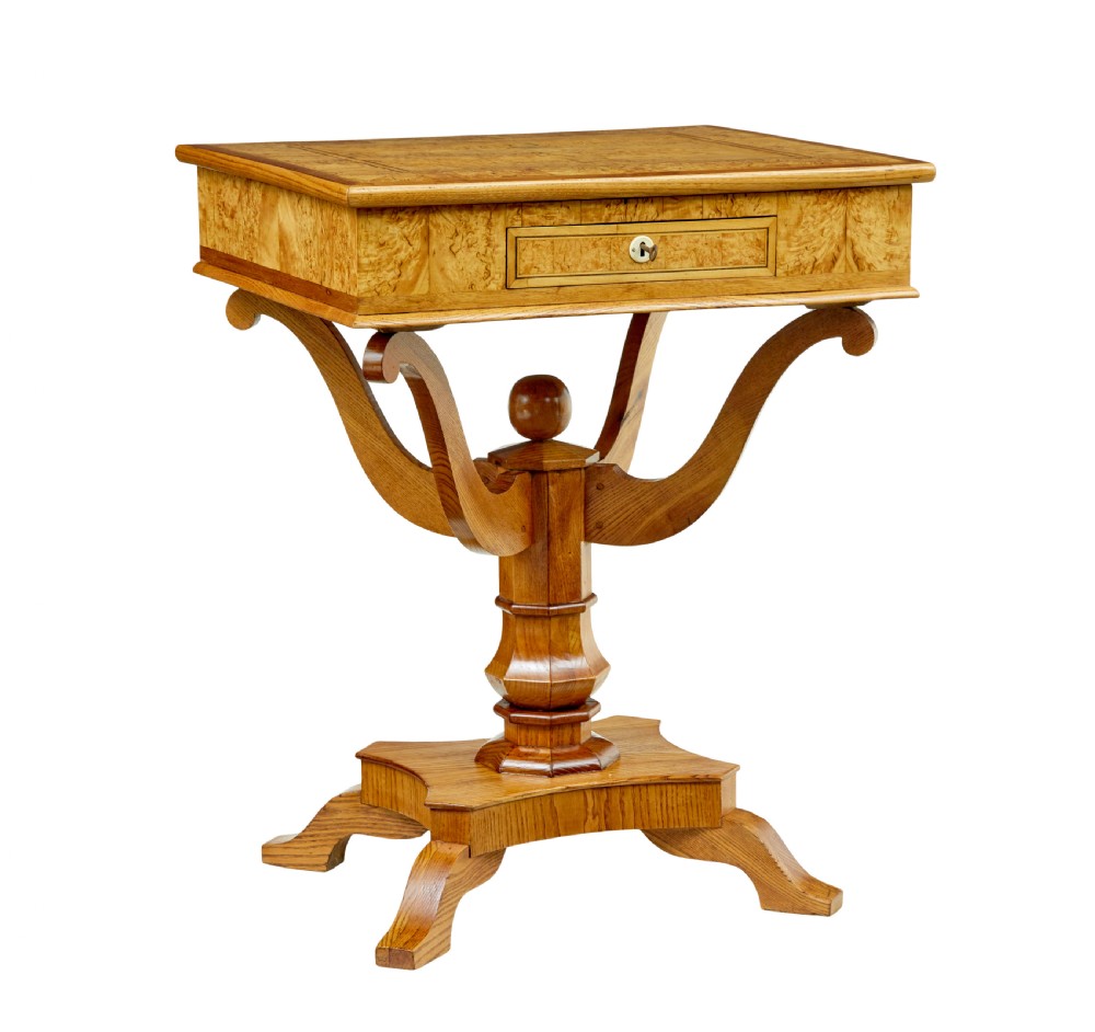 A 19th-century Scandinavian occasional table made of burr birch and elm with a single drawer, S-curved supports, a turned central pedestal, and a four-footed base.
