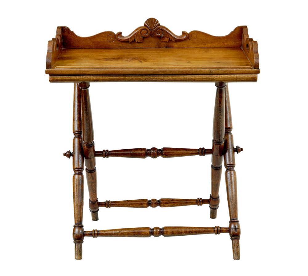 A 19th-century solid oak butler tray with carved gallery handles resting on a folding x-frame stand with turned spindles. View II