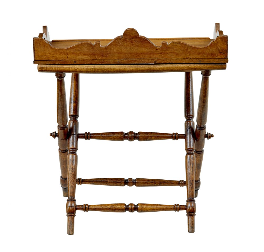 A 19th-century solid oak butler tray with carved gallery handles resting on a folding x-frame stand with turned spindles. View V