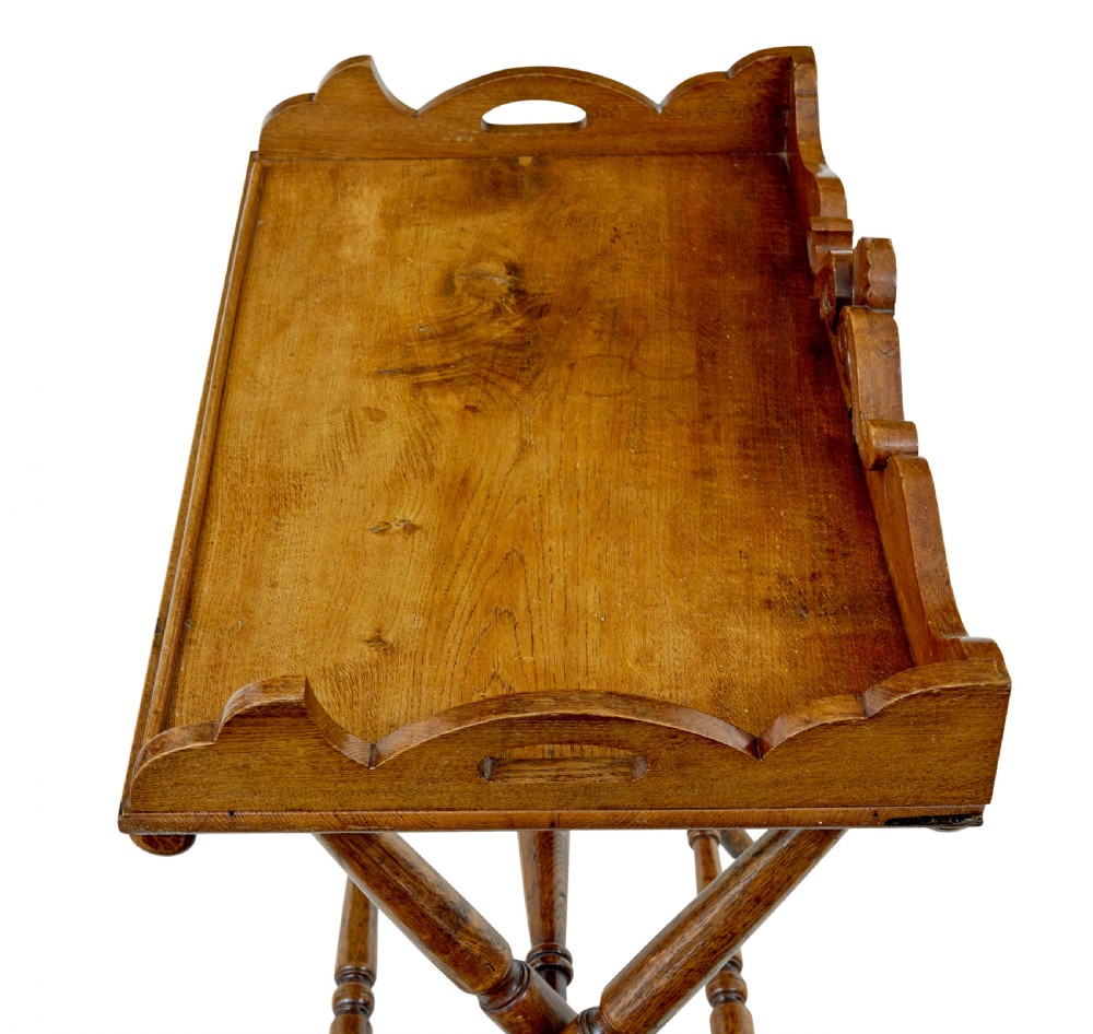 A 19th-century solid oak butler tray with carved gallery handles resting on a folding x-frame stand with turned spindles. View VII
