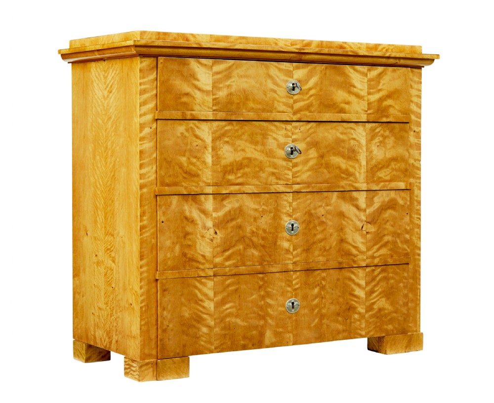 A 19th-century Swedish Biedermeier chest of drawers crafted from flame birch veneer with four horizontal drawer fronts, metal escutcheons, and square block feet.