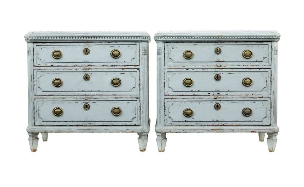 A pair of 19th-century pale blue-grey painted chests of drawers with three drawers each, brass ring handles, fluted corners, and faux marble tops.