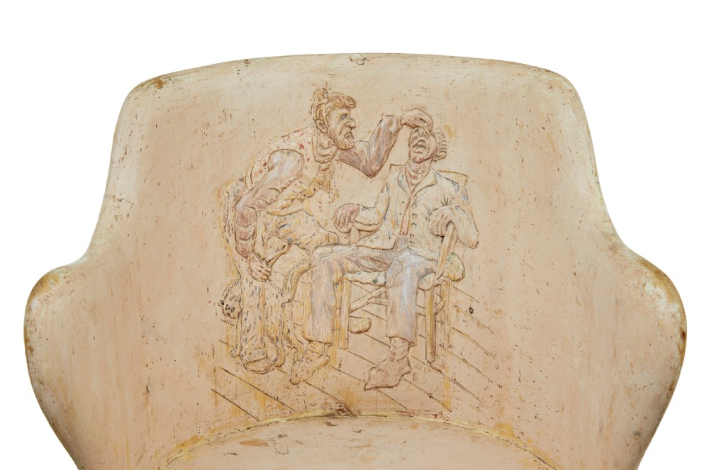An antique cream-painted dugout armchair carved from a single timber section with relief floral scrollwork and hand-painted figures on the backrest. View II