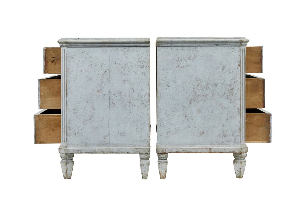 A pair of 19th-century Gustavian style painted chests of drawers with three drawers each, brass pulls, fluted side columns, and distressed pale grey paint. View III