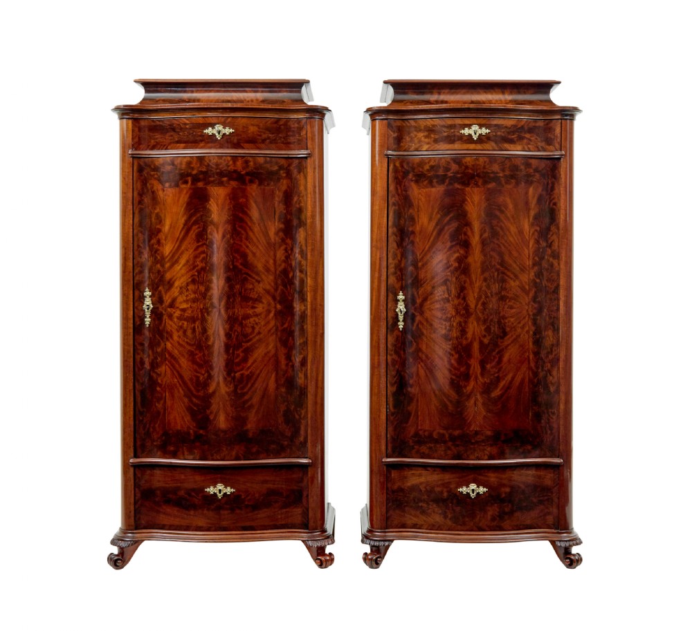 A pair of 19th-century Scandinavian tall mahogany cupboards featuring serpentine fronts, flame veneer panels, and ornate brass keyhole escutcheons. View II