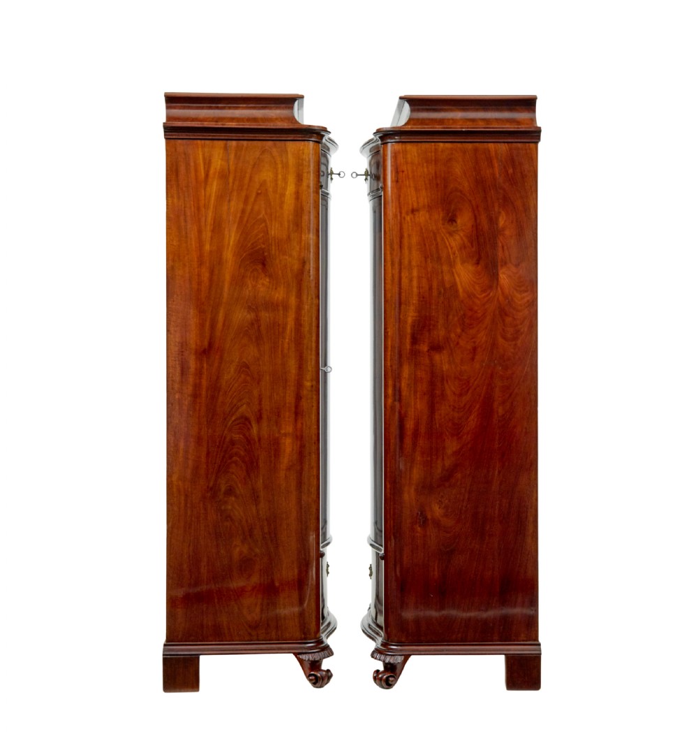 A pair of 19th-century Scandinavian tall mahogany cupboards featuring serpentine fronts, flame veneer panels, and ornate brass keyhole escutcheons. View VI
