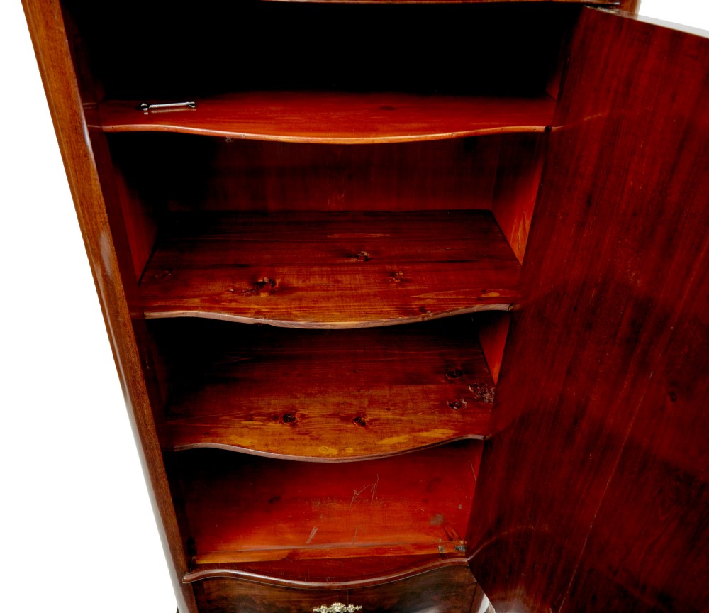 A pair of 19th-century Scandinavian tall mahogany cupboards featuring serpentine fronts, flame veneer panels, and ornate brass keyhole escutcheons. View XI