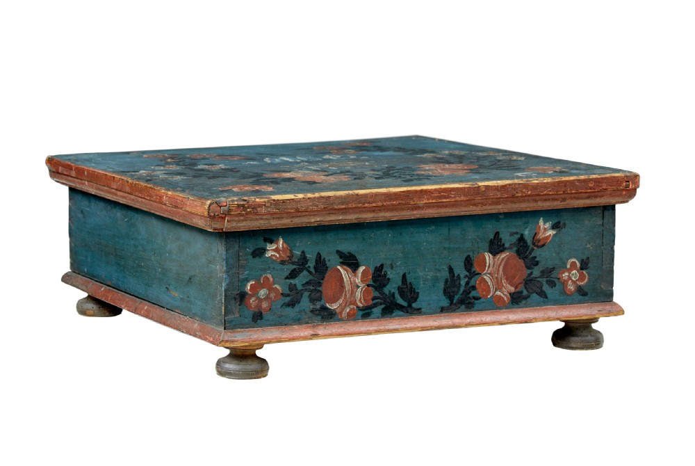 A 19th-century rectangular pine box painted teal blue with red floral motifs and small turned feet.
