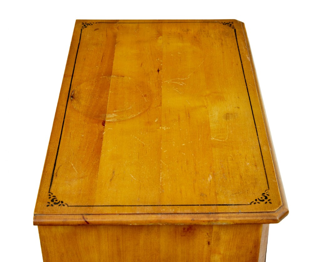 A tall Swedish honey-coloured wooden chest of four drawers featuring hand-painted black corner flourishes and turned knobs. View III