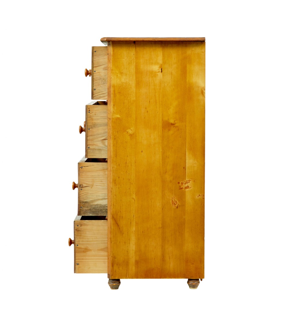 A tall Swedish honey-coloured wooden chest of four drawers featuring hand-painted black corner flourishes and turned knobs. View VII