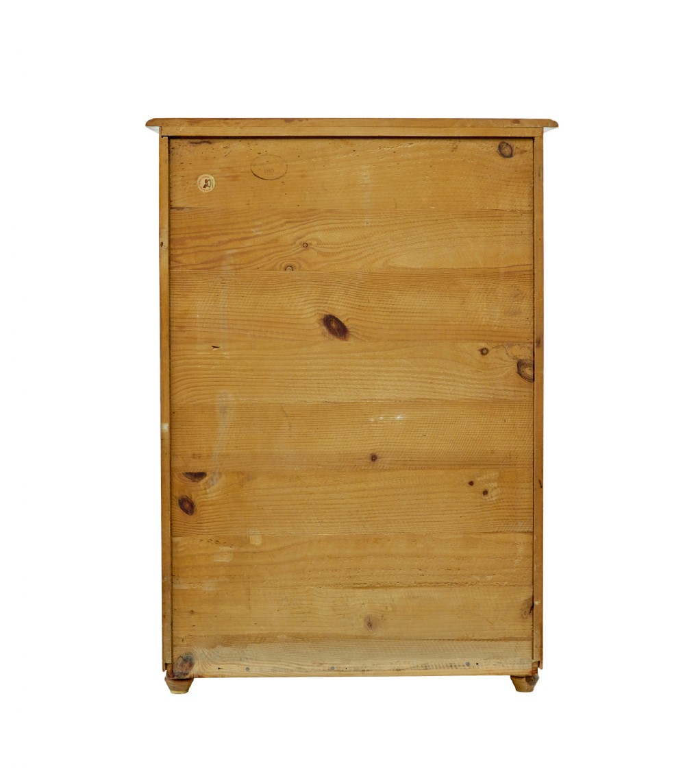 A tall Swedish honey-coloured wooden chest of four drawers featuring hand-painted black corner flourishes and turned knobs. View IX