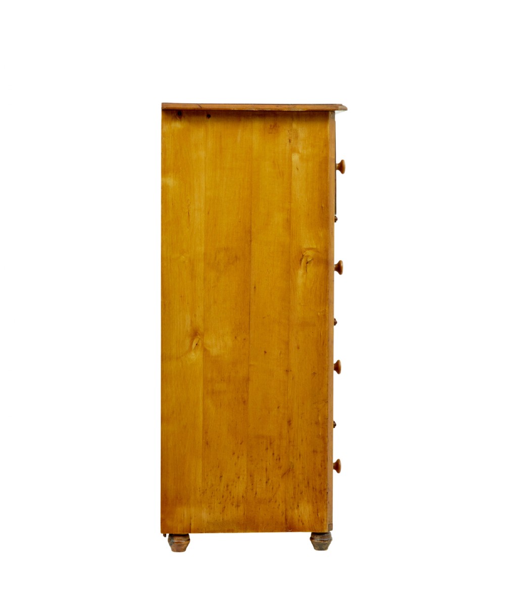 A tall Swedish honey-coloured wooden chest of four drawers featuring hand-painted black corner flourishes and turned knobs. View X