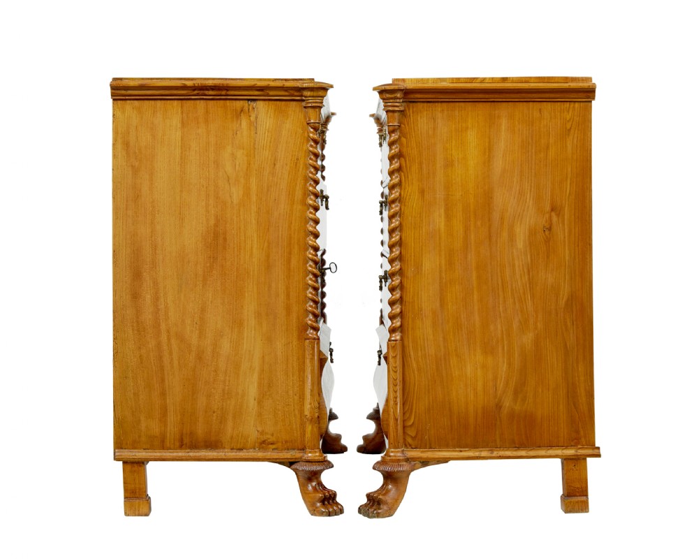 A matching pair of mid-19th-century Swedish carved elm chests of drawers featuring four drawers, barley twist side columns, carved paw feet, and brass hardware. View V