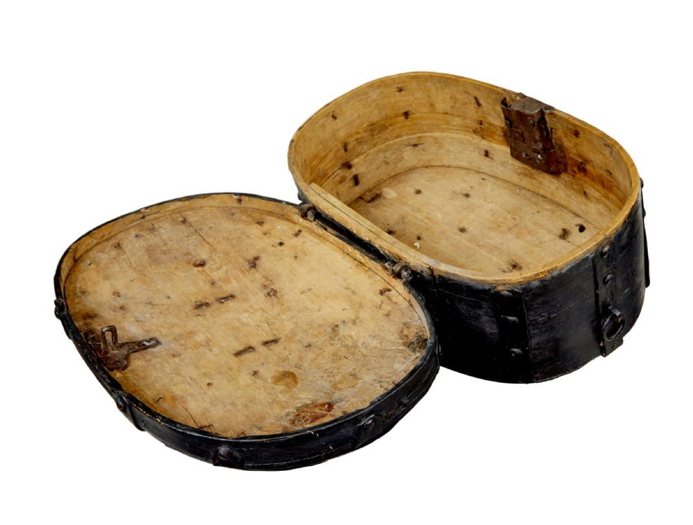 A 19th-century oval black-painted pine box featuring heavy iron straps, rivets, a top handle, and a decorative keyhole escutcheon. View VI