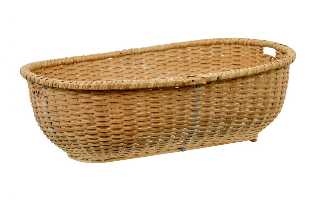 A large oval hand-woven pine basket with integrated handles and a reinforced wooden base.