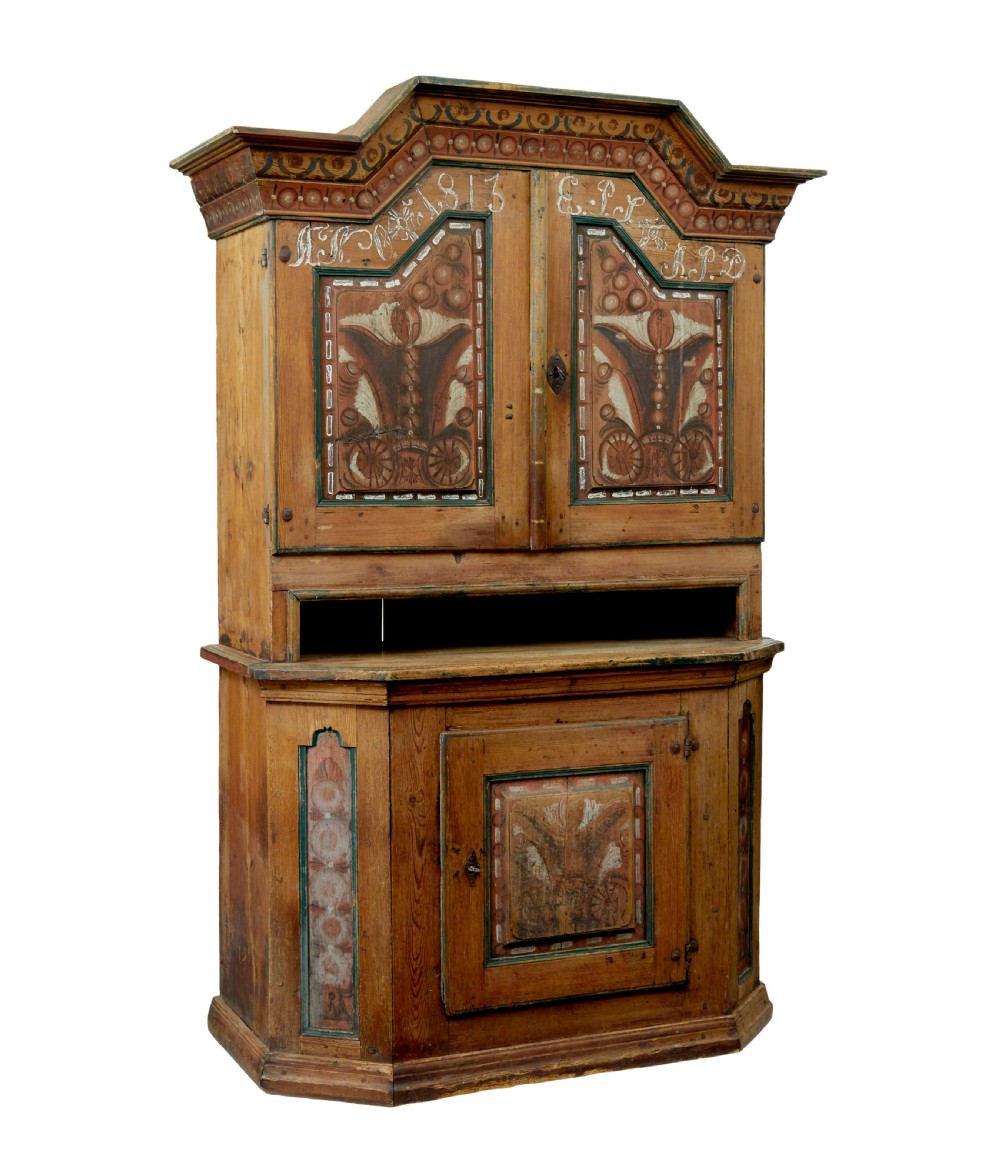An early nineteenth-century Swedish painted pine cupboard featuring a shaped upper section with painted panel doors dated 1813 above an open shelf and lower cabinet.