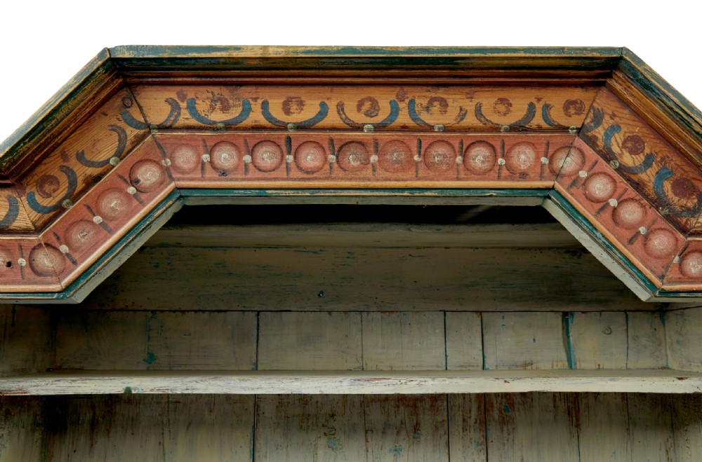 An early nineteenth-century Swedish painted pine cupboard featuring a shaped upper section with painted panel doors dated 1813 above an open shelf and lower cabinet. View X