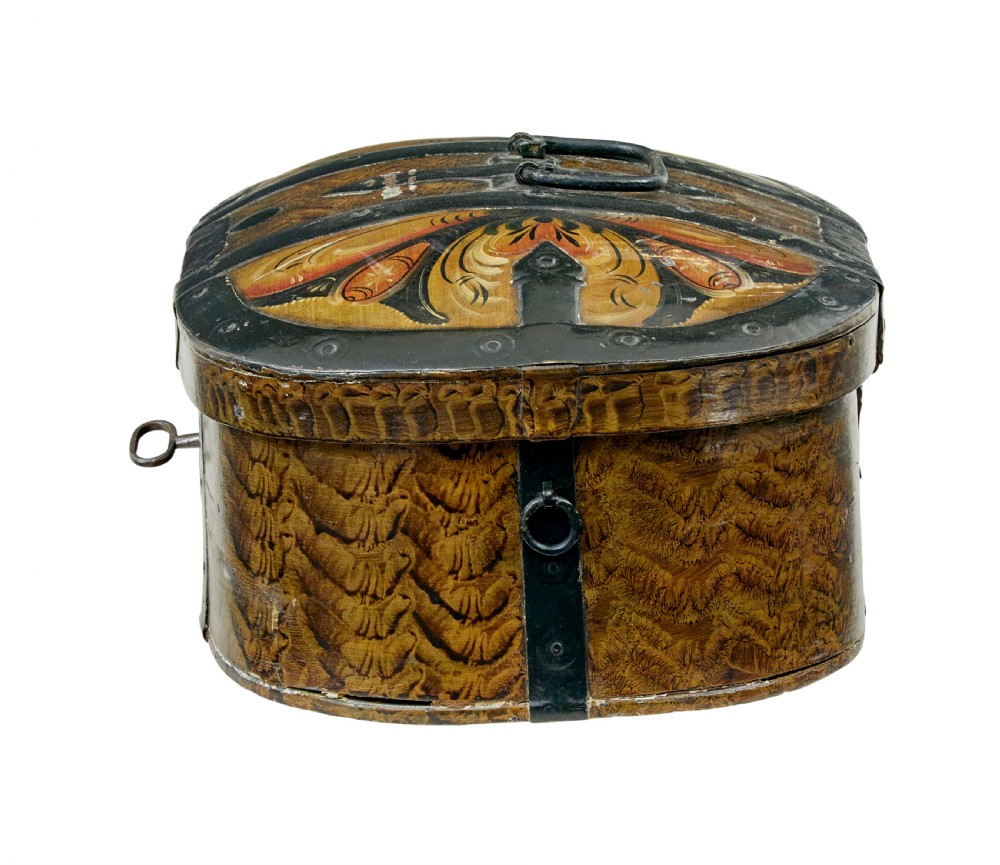 An oval 19th-century Scandinavian painted wooden box featuring black iron straps, a top metal handle, comb-painted sides, and hand-painted floral motifs on the curved lid. View IV