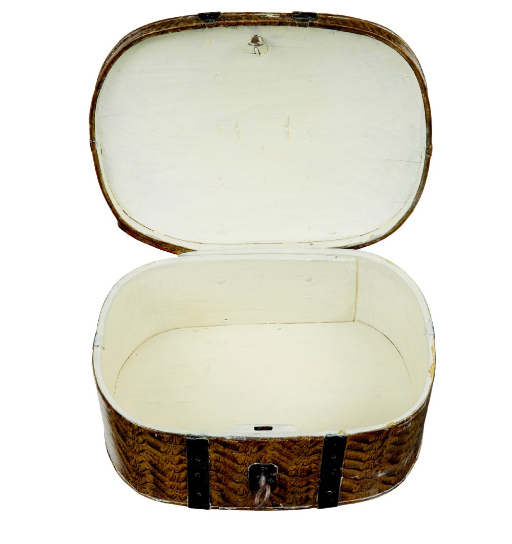 An oval 19th-century Scandinavian painted wooden box featuring black iron straps, a top metal handle, comb-painted sides, and hand-painted floral motifs on the curved lid. View VI