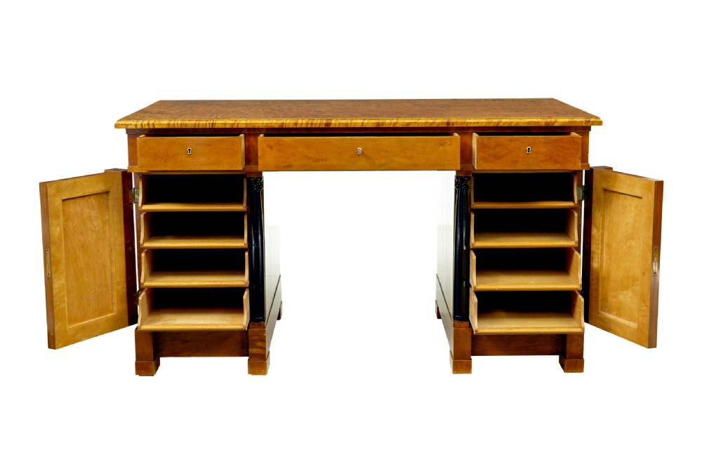 A Swedish Empire Revival pedestal desk crafted from golden flame birch veneer featuring three frieze drawers, ebonised column accents, and geometric inlaid cabinet doors. View III