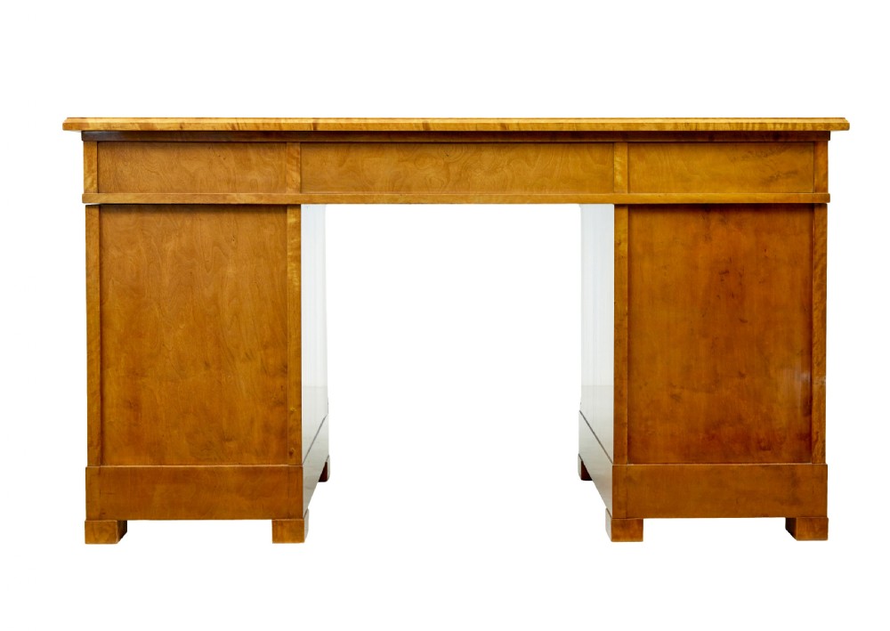 A Swedish Empire Revival pedestal desk crafted from golden flame birch veneer featuring three frieze drawers, ebonised column accents, and geometric inlaid cabinet doors. View V