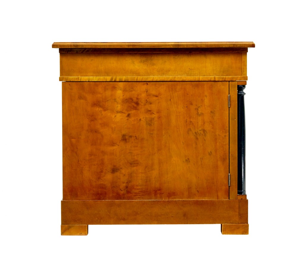 A Swedish Empire Revival pedestal desk crafted from golden flame birch veneer featuring three frieze drawers, ebonised column accents, and geometric inlaid cabinet doors. View VI