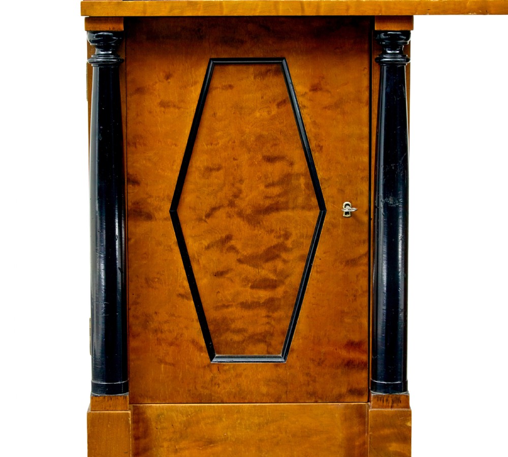 A Swedish Empire Revival pedestal desk crafted from golden flame birch veneer featuring three frieze drawers, ebonised column accents, and geometric inlaid cabinet doors. View IX