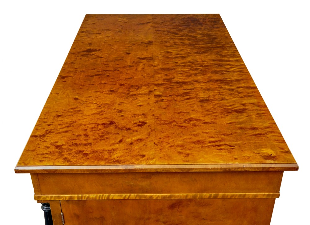 A Swedish Empire Revival pedestal desk crafted from golden flame birch veneer featuring three frieze drawers, ebonised column accents, and geometric inlaid cabinet doors. View XI