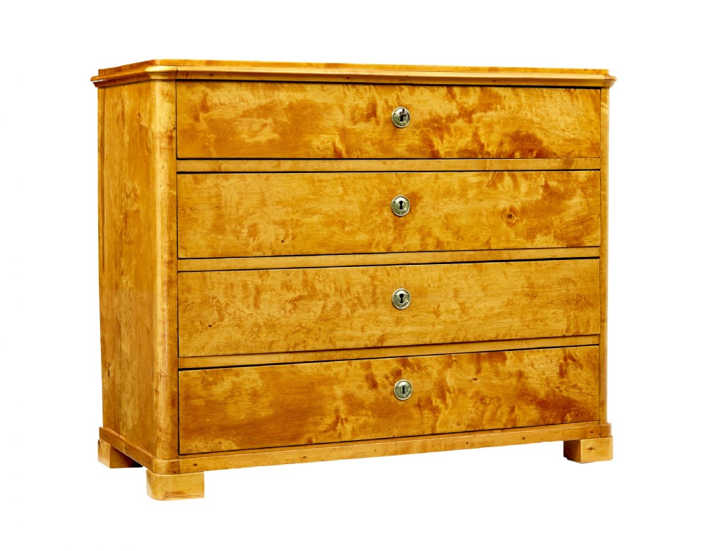 A nineteenth-century Scandinavian chest of drawers crafted from golden birch with four wide drawers and keyhole escutcheons.