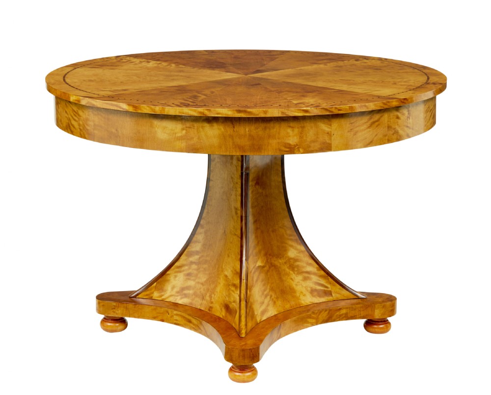 A circular golden flame birch centre table featuring a starburst-patterned veneer top, decorative inlaid rim border, sweeping concave pedestal stem, and quadform base with bun feet. View II