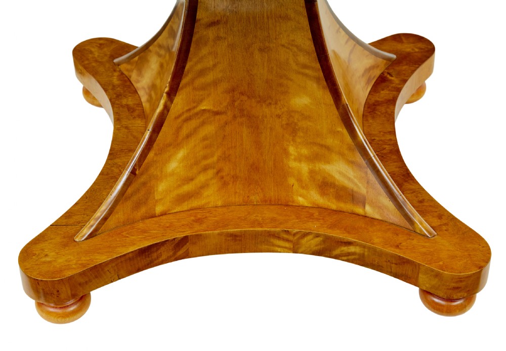 A circular golden flame birch centre table featuring a starburst-patterned veneer top, decorative inlaid rim border, sweeping concave pedestal stem, and quadform base with bun feet. View VII