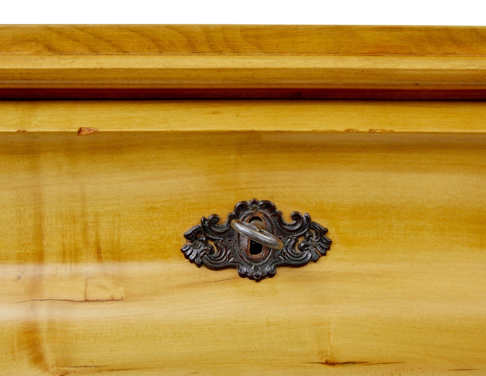 A 19th-century Swedish chest of drawers constructed from honey-toned flame birch with four drawers, keyhole escutcheons, and a scalloped base apron. View II