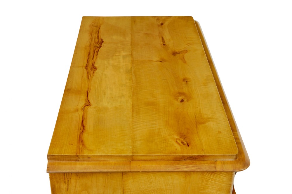 A 19th-century Swedish chest of drawers constructed from honey-toned flame birch with four drawers, keyhole escutcheons, and a scalloped base apron. View III