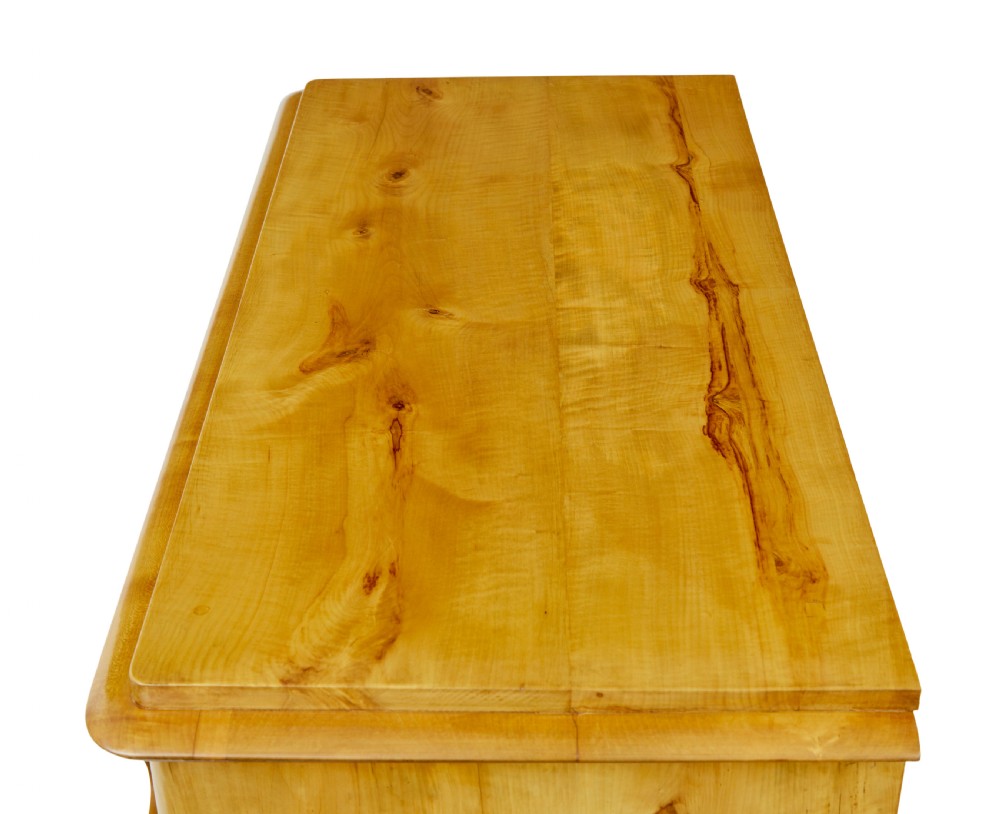 A 19th-century Swedish chest of drawers constructed from honey-toned flame birch with four drawers, keyhole escutcheons, and a scalloped base apron. View IV