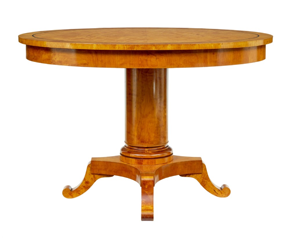 A late 19th-century Swedish circular centre table in golden satin birch veneer, featuring ebonised inlay, a cylindrical pedestal column, and a four-point plinth with scroll feet. View III