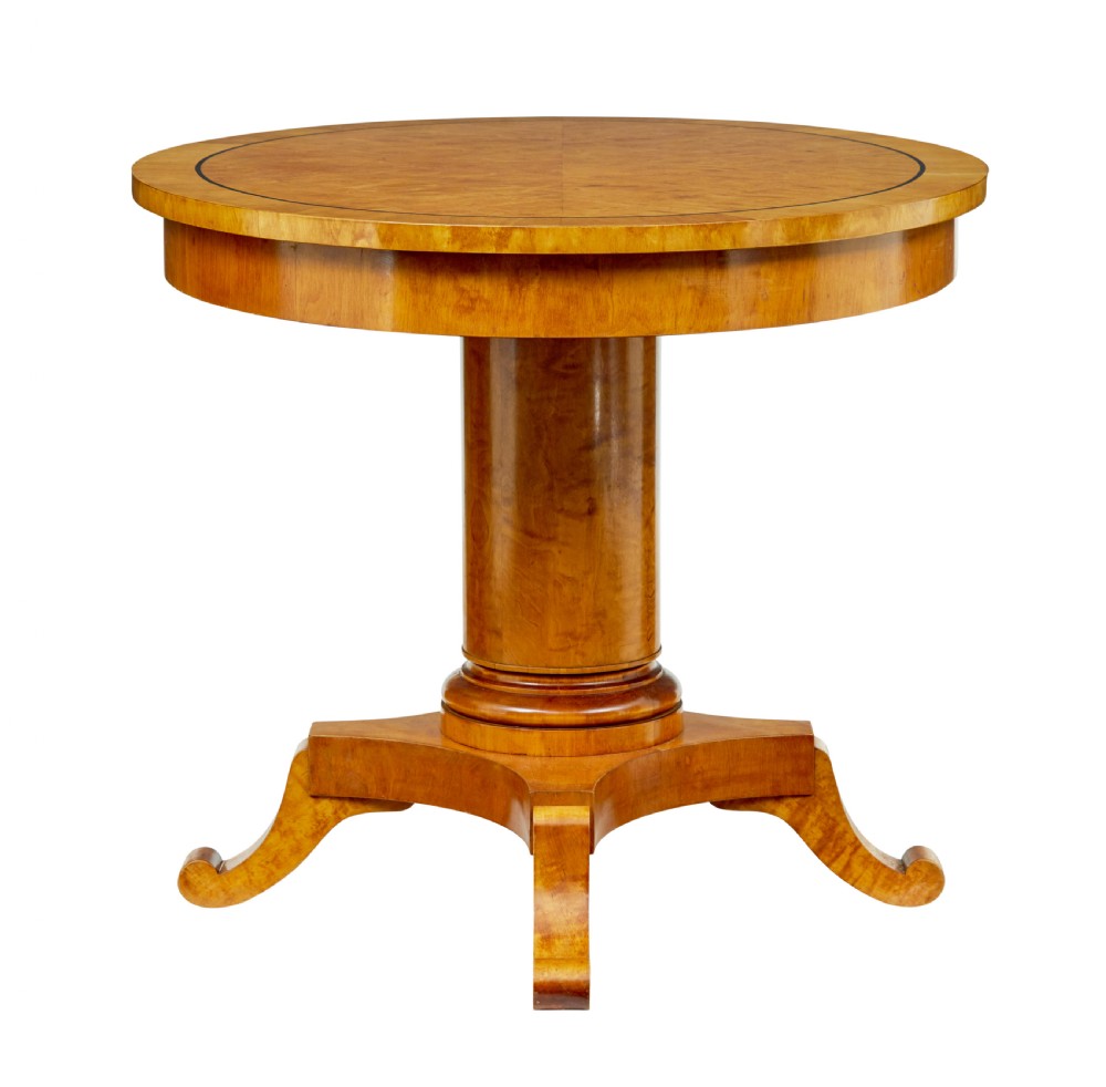 A late 19th-century Swedish circular centre table in golden satin birch veneer, featuring ebonised inlay, a cylindrical pedestal column, and a four-point plinth with scroll feet. View IV