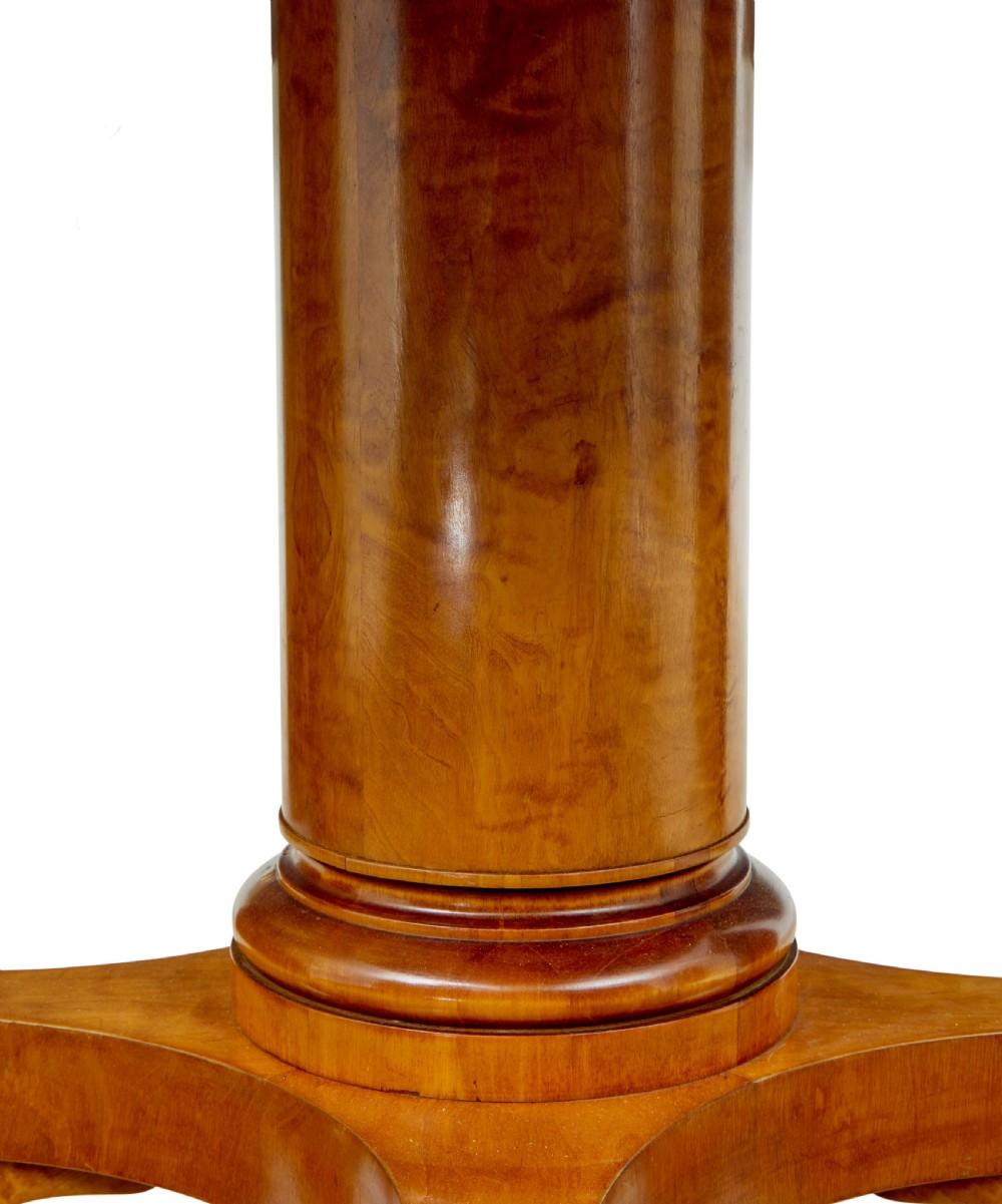 A late 19th-century Swedish circular centre table in golden satin birch veneer, featuring ebonised inlay, a cylindrical pedestal column, and a four-point plinth with scroll feet. View VII