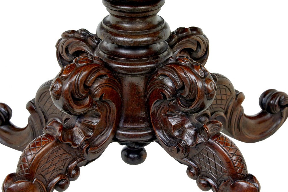 A 19th-century oval wood centre table featuring a flame mahogany veneered top, beaded apron moulding, turned central column, and carved scroll feet. View III