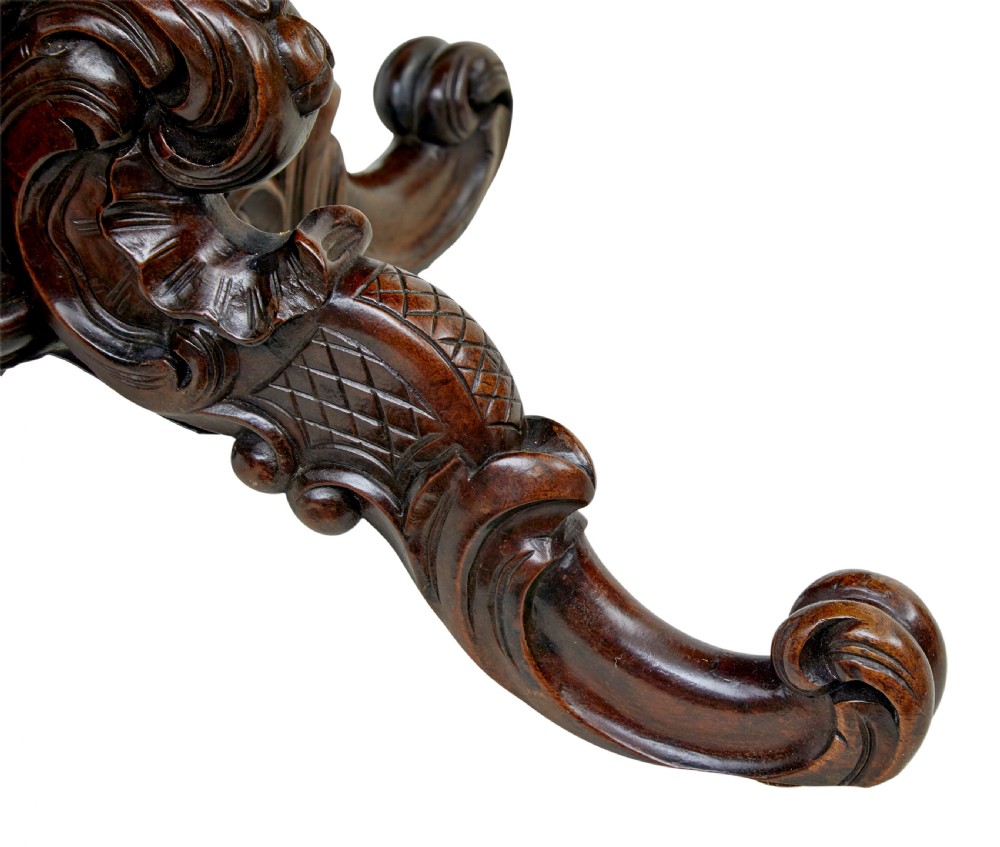 A 19th-century oval wood centre table featuring a flame mahogany veneered top, beaded apron moulding, turned central column, and carved scroll feet. View IV