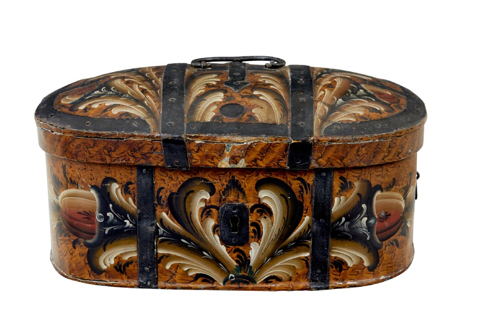 A 19th-century oval Scandinavian wooden box painted in warm ochre with dark floral scrollwork and fitted with black iron banding.