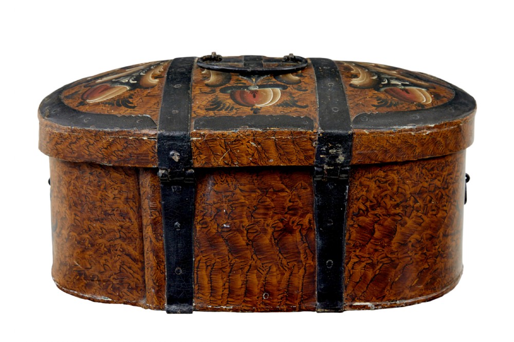 A 19th-century oval Scandinavian wooden box painted in warm ochre with dark floral scrollwork and fitted with black iron banding. View V