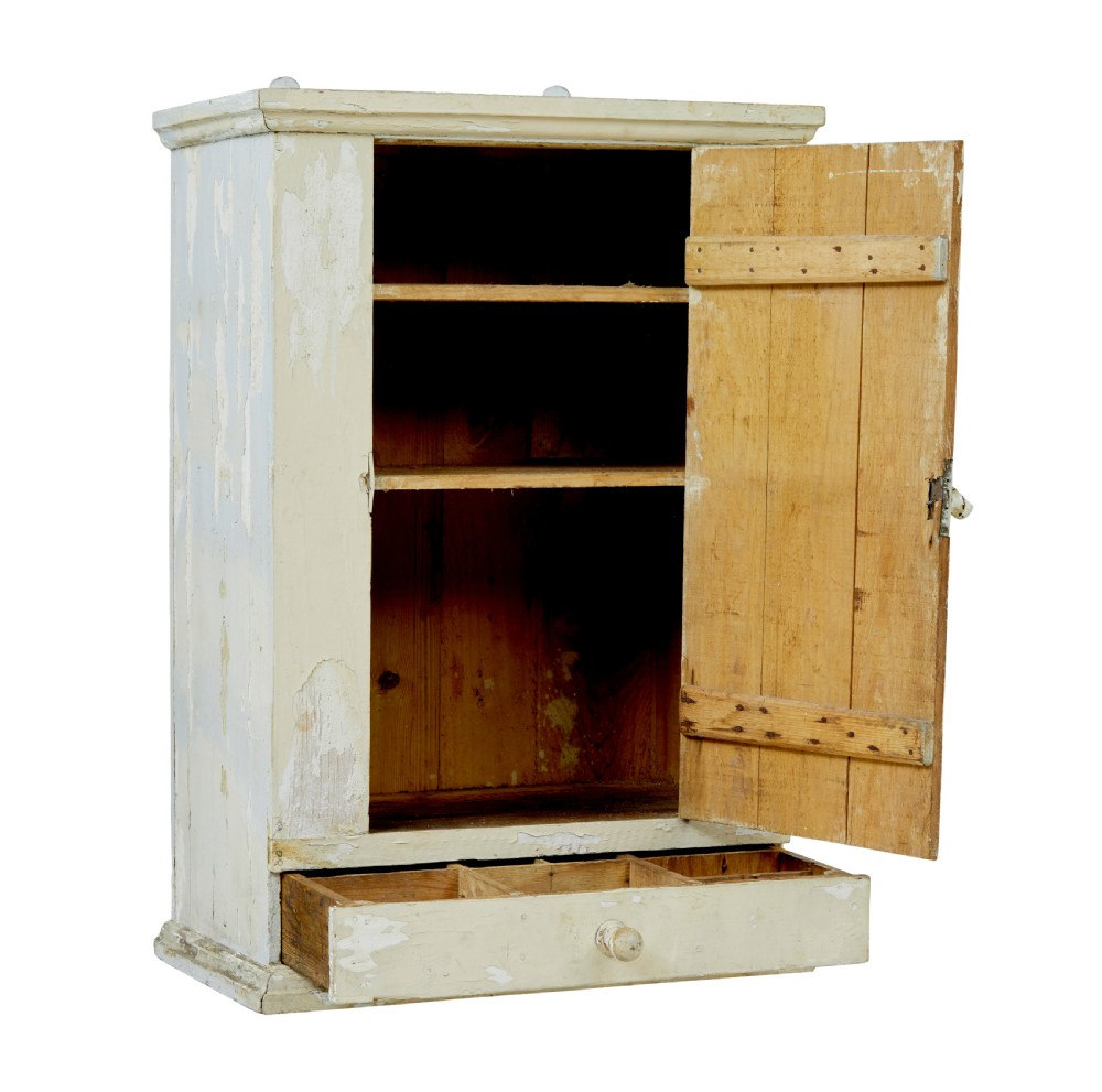 A 19th-century Scandinavian pine wall cupboard with a distressed cream painted finish, a single panelled door, and one lower drawer. View II