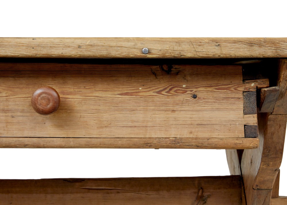 A 19th-century Swedish pine kitchen table featuring an X-frame base with pegged stretcher joints and a single central drawer. View X